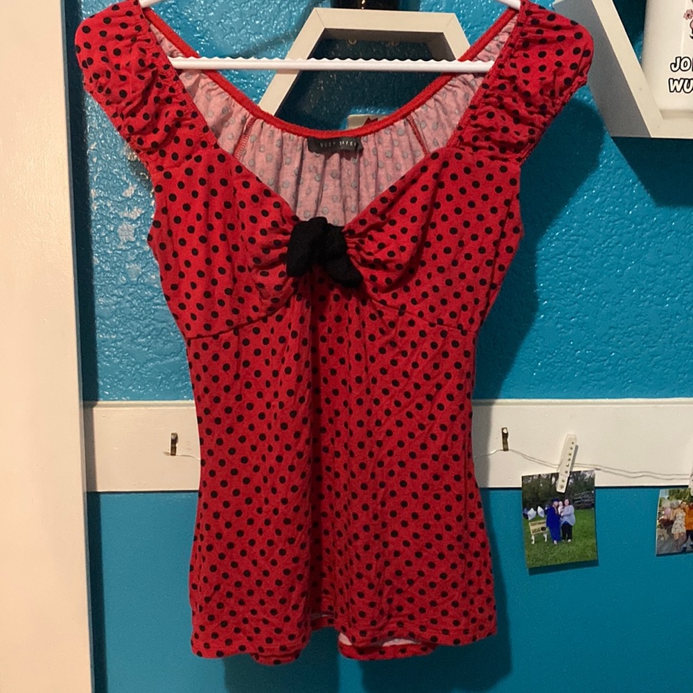 Red shirt with black polka dots all over and a black bow in the middle